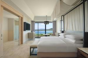 a bedroom with a large white bed and a large window at Manado Marriott Resort & Spa in Manado +25 photos