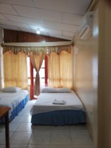 two beds in a room with a window at Hostal Miconia in Puerto Ayora +7 photos