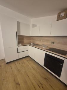 a kitchen with white cabinets and a wooden floor at Luna in Lierna