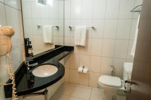 a bathroom with a sink and a toilet at Firenze Business Hotel in Palhoça