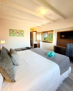 a large white bed with two blue towels on it at Berna Hotel & Spa in Villa General Belgrano