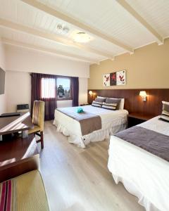 a hotel room with two beds and a desk at Berna Hotel & Spa in Villa General Belgrano