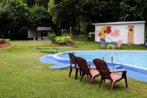 two chairs and a table next to a swimming pool at Manoir Charlevoix in La Malbaie
