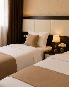 a hotel room with two beds and a table with a lamp at Green City Hotel ШАХРИСАБЗ in Khujand