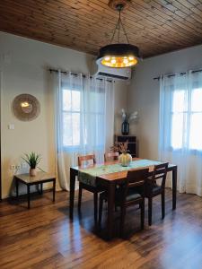 a dining room with a table and chairs and windows at Betty's Garden House in Nea Anchialos