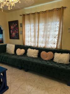 a green couch with pillows on it in front of a window at Elite stays in Santa Cruz