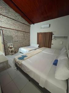 a bedroom with two beds and a brick wall at Casa de Praia Recanto Flecheiras in Trairi +8 photos