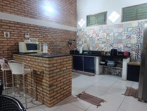 a kitchen with a brick wall and a counter with a microwave at Casa de Praia Recanto Flecheiras in Trairi