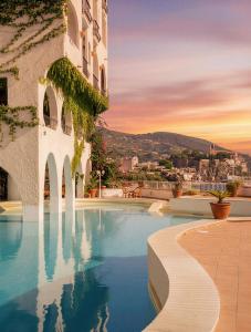 a hotel swimming pool with a sunset in the background at Hotel Carasco in Lipari