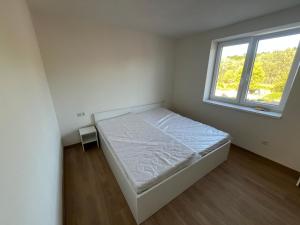 a white bedroom with a bed and a window at Hakro Jevisovka in Jevišovka