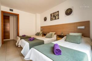 three beds in a room with purple pillows on them at Hanami Suite in Lloret de Mar +12 photos