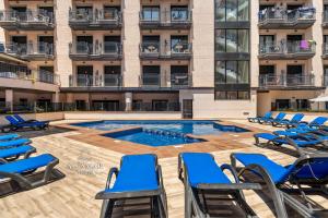 a swimming pool with chairs and a building at Hanami Suite in Lloret de Mar
