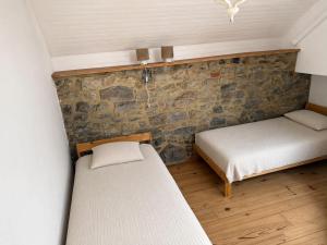a room with two beds and a stone wall at La Petite Grange in Aywaille