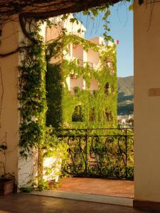 a building covered in green ivy next to a fence at Hotel Carasco in Lipari
