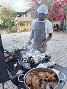 a man is cooking food on a grill at Kio Farm Retreat in Kiserian