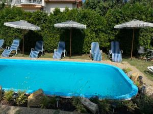 a group of chairs and umbrellas next to a pool at Vázsonyi Vendégház in Balatonfüred