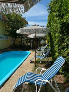 a group of chairs and an umbrella next to a swimming pool at Vázsonyi Vendégház in Balatonfüred