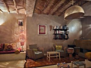 a living room with a couch and chairs and a book shelf at RIAD AMAN SKOURA in Skoura