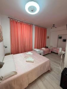 a bedroom with two beds with pink curtains at Villa Santa Chiara in Loreto