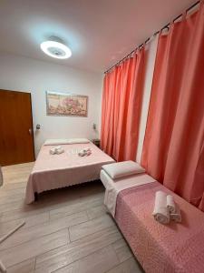 two beds in a room with red curtains at Villa Santa Chiara in Loreto