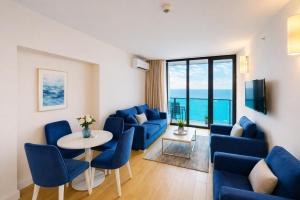 a living room with blue chairs and a table at Orbi City Panorama Hotel & Sea View Balcony in Batumi