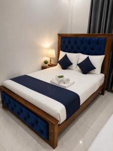 a bedroom with a large bed with a blue headboard at ANABEE HOLIDAY Inn in Jaffna