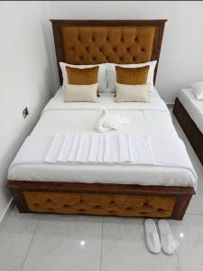a bed with a wooden headboard and two white shoes at ANABEE HOLIDAY Inn in Jaffna +3 photos