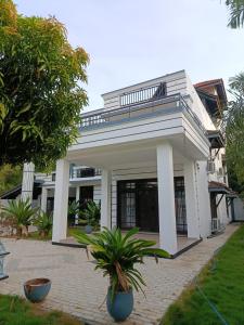 a white house with a porch and palm trees at ANABEE HOLIDAY Inn in Jaffna