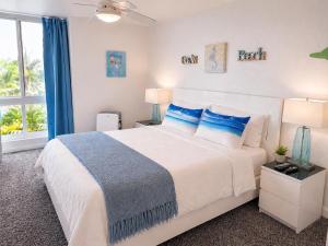 a bedroom with a large white bed with blue pillows at SolMar Breeze - 1BR Condo at North Coast Village - Heated Pools, Hot Tubs & Steps to Beach, Oceanside Harbor and Pier in Oceanside +13 photos