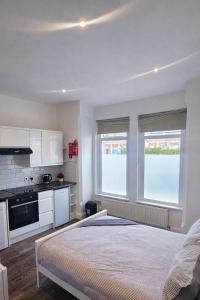 a white bedroom with a large bed and two windows at Studio Flat London in The Hyde
