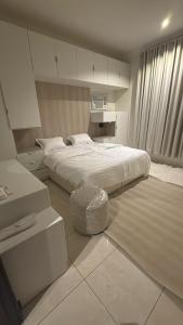 a white bedroom with a bed and a stool at شقق وهل in Dammam