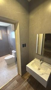 a bathroom with a sink and a toilet and a mirror at شقق وهل in Dammam +10 photos