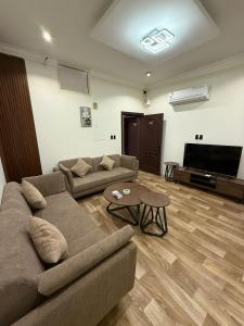 a living room with two couches and a flat screen tv at شقق وهل in Dammam