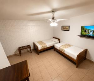 a room with two beds and a tv on the wall at Borus Hostel in Puerto Iguazú