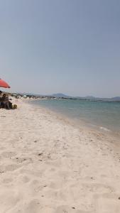 a sandy beach with people sitting under an umbrella at Azzurra Haven in Berchidda +16 photos