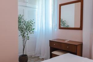 a bedroom with a dresser and a mirror and a plant at Corfu Glyfada Beach Apartment 40 in Glyfada