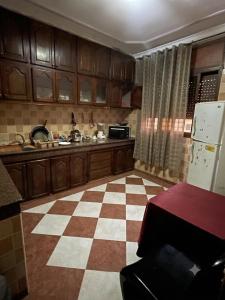 a kitchen with wooden cabinets and a checkered floor at MEFTAH lkhir hay nour in Safi