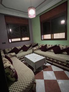 a living room with couches and a table and windows at MEFTAH lkhir hay nour in Safi