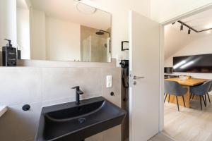 a bathroom with a black sink and a table at Glückszeit Apartments Gießen in Gießen