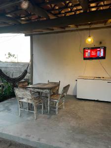 a table and chairs with a television on the wall at Suite Adam 3 em Caraíva com piscina 900m da Vila in Caraíva