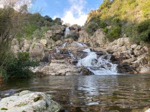 a waterfall on a river with rocks and water at Azzurra Haven in Berchidda