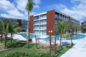 an apartment building with a swimming pool and palm trees at Porto de Galinhas, Muro alto - PÉ NA AREIA in Ipojuca