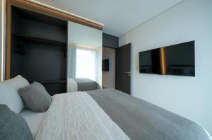 a bedroom with a bed and a flat screen tv at Porto de Galinhas, Muro alto - PÉ NA AREIA in Ipojuca