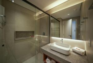 a bathroom with a sink and a glass shower at Porto de Galinhas, Muro alto - PÉ NA AREIA in Ipojuca +10 photos