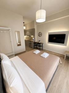 a bedroom with a large white bed with a flat screen tv at Above Apartments near the Airport in Artemida