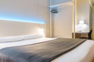 
a bedroom with a bed and a lamp at Vértice Roomspace in Madrid

