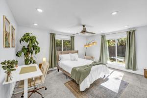 a bedroom with a bed and a desk and windows at Hot Tub Fire Pit 10 Min From DFW Airport in Irving