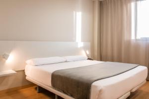 a white bed in a room with a window at Vértice Roomspace in Madrid