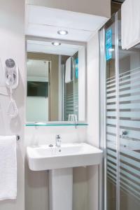 un baño con lavabo y espejo en Vértice Roomspace, en Madrid