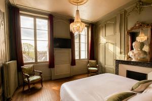 a bedroom with a bed and two chairs and a fireplace at La Villa Du Temple - Climatisation in Auxerre